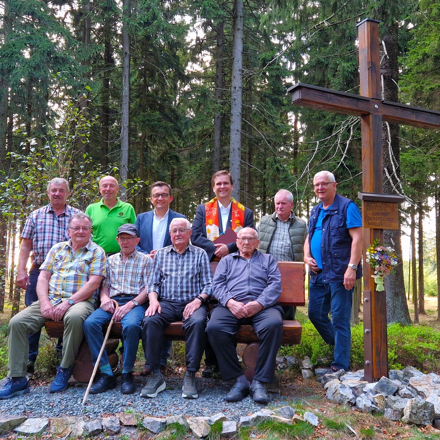 Dekan Detlef Pötzl segnete das restaurierte Gipfelkreuz. Auf der Bank von rechts die noch lebenden Bergfreunde Andreas „Siegmund“ Müller und Franz Schlee, sowie die Helfer und Bürgermeister Jens Korn (hinten 3.v.li)